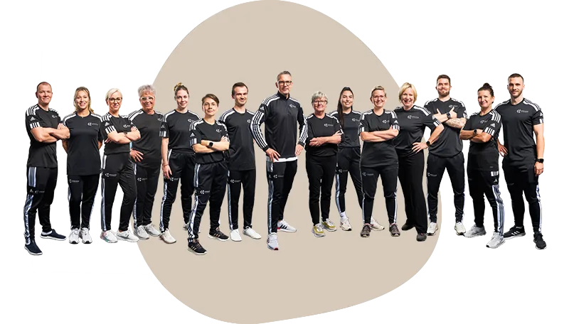Das Team des Therapiezentrums Orbanke, fünfzehn Kolleg:innen in schwarzen Trainingsshirts, vor einer sandfarbenen Fläche.